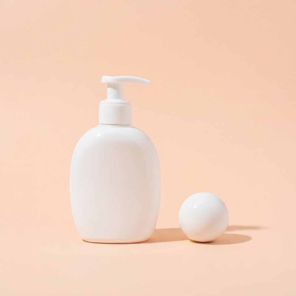 A glossy white pump bottle beside a small sphere on a pastel peach background